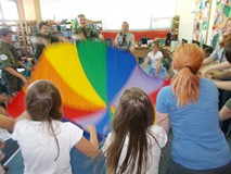 Harcerze wspólnie z dziećmi trzymają chustę animacyjną