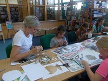 Bibliotekarka pomaga dzieciom podczas zajęc plastycznych