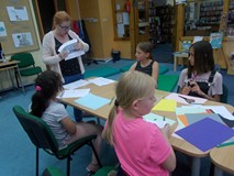 Bibliotekarka tłumaczy dzieciom, co będzie ich zadaniem podczas pracy plastycznej