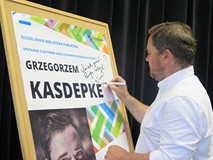 Grzegorz Kasdepke w Koszalińskiej Bibliotece Publicznej podpisuje plakat promocyjny