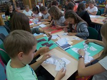 dzieci przy stołach wykonują prace plastyczne