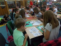 dzieci przy stołach wykonują prace plastyczne