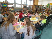 dzieci przy stołach wykonują prace plastyczne