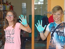 Chłopiec i dziewczynka pokazują ręce ufarbowane niebieską kredką