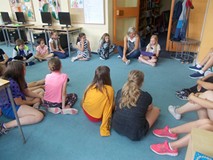 Dzieci siedzą w kole na krzesłach podczas wspólnej zabawy