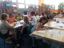 Dzieci siedzą przy stole podczas wykonywania pracy plastycznej