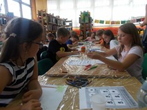 Dzieci siedzą przy stole podczas wykonywania pracy plastycznej