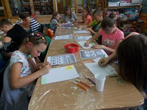 Dzieci siedzą przy stole podczas wykonywania pracy plastycznej