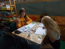 Dwie dziewczynki siedzą przy stole wykonując pracę plastyczną