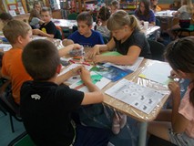 Dzieci siedzą przy stole podczas wykonywania pracy plastycznej