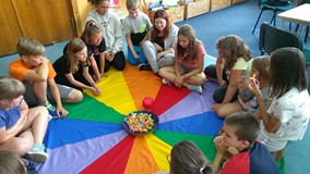 Dzieci siedzą na chuście i grają z bibliotekarką w grę