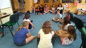 Dzieci siedzą na dywanie i dyskutują o prawach zwierząt