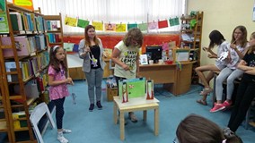 Dzieci z bibliotekarką występują w teatrze papierowym