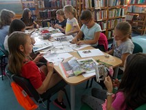 Dzieci siedzą przy stole i wykonują prace plastyczne