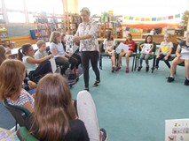 Prowadząca pokazuje dzieciom prace dzieci