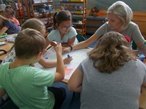 Bibliotekarka wraz z dziećmi wykonuje plakat