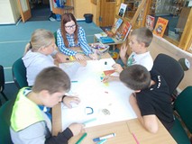 dzieci wspólnie z bibliotekarką tworza plakat