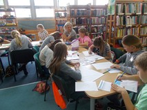 dzieci przy stołach wykonują prace plastyczne