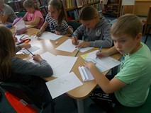 Dzieci przy stole wykonują pracę plastyczną