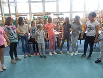 Dzieci stoją w kole i przekładają koło