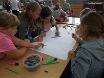 Dziewczynki przy stoliku wykonują wspólnie plakat