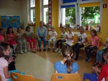 Dzieci i prowadząca siedzą na krzesełkach w kręgu - rozpoczyna się drugi dzień warsztatów BEZPIECZNI