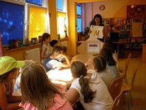 Pani Wiola pokazuje dzieciom przykładowe karty do teatrzyku Kamishibai