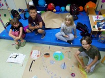 Filia nr 9. Dwie dziewczynki i dwóch chłopców siedzi przy swojej pracy plastycznej, która przedstawi