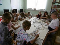 Filia nr 11. Cztery czteroosobowe drużyny przy dużym stole. Każda drużyna wykonuje pracę plastyczną 