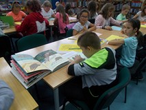 Filia nr 12. Dzieci siedzą w dwóch rzędach przy stołach i wykonują pracę plastyczną na temat dzikich