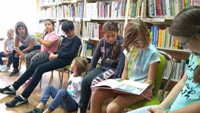 Filia nr 15. Dzieci przed zajęciami w bibliotece. Trzy dziewczynki oglądają książkę.