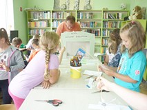Filia nr 1. Dzieci otaczają stół. Na stole makieta z napisem Teatr Zielona Biblioteka. Za makietą st