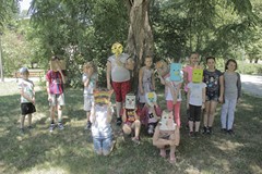 Filia nr 3. Dzieci stoją w parku pod drzewem, mają na sobie własnoręcznie wykonane maski zwierząt: k