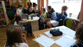 Filia nr 3. Bibliotekarz KBP, Piotr Świerczyński siedzi przy stoliku i czyta książkę, otaczającym go