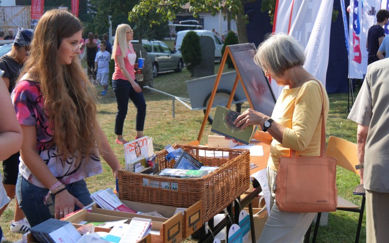 Bibliotekarz przy stoisku promocyjnym Koszalińskiej Biblioteki Publicznej na festynie...