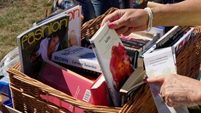 Czytelniczka przegląda książki umieszczone w koszu bookcrossingowym