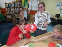 Bibliotekarka pozuje z dziećmi i ich pracami plastycznymi