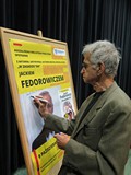 Jacek Fedorowicz podpisuje plakat promujący spotkanie w Koszalińskiej Bibliotece Publicznej