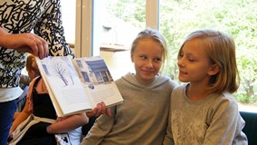 Dwiedziewczynki oglądają ilistrację w książce Cezarego Harasimowicza 