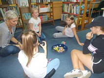 Dzieci siedzą na dywanie w kole podczas wspólnej zabawy