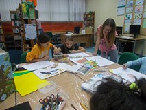 Dwie dziewczynki robią rysunek, podczas gdy jedna z dziewczynek im asystuje