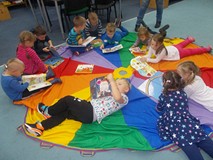 Dzieci siedzą na chuście i oglądają książki