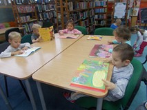 Dzieci siedzą przy stole i oglądają książeczki