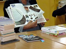 Bibliotekarka  prezentuje książki dla dzieci o tematyce ekonomicznej