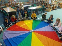 Dzieci siedzą na chuście animacyjnej i czytaja ksiązkę