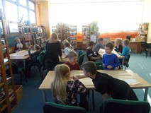 Dzieci siedzą przy stołach i pracują w grupach