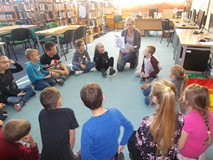 Bibliotekarka pokazuje dzieciom ilustracje przedstawiającą ducha