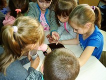 Dzieci skupione wokół stolika dzielą koraliki według kolorów