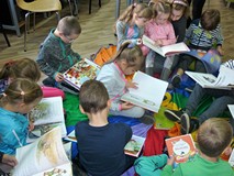 Dzieci przeglądają książki siedząc na podłodze