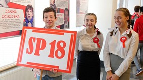 Trzyosobowa drużyna ze SP nr 18. Chłopak trzyma kartkę z dużym napisem SP 18, za nim dwie dziewczyny